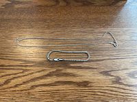 Photo showing a sterling silver chain necklace and matching bracelet laid flat on a wooden surface.