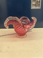Side view of cranberry glass dish showing ruffled edges and spiral pattern