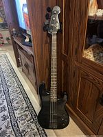 Full front view of black Fender Jazz Bass Special bass guitar against wood cabinet background