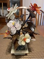 Glass flower bouquet showing white, pink, orange, and red glass flowers with metal leaves on a marble base.
