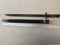 Full view of bayonet alongside scabbard with ruler for length reference