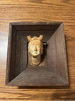 Top down view of a pottery head mounted on a square wooden frame with concentric stepped grooves