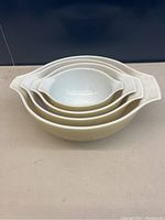 Stacked view of four Pyrex nesting bowls with mushroom pattern on exterior, showing handles.