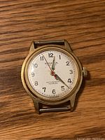 Front view of gold-tone Roadania Swiss watch showing white dial with black numerals and red/tone hands, marked 17 jewels, antimagnetic and Incabloc.