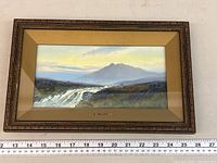 Framed landscape painting with river and mountain scene, measuring approximately 26 inches wide.