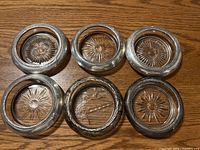 Top view of four matching round coasters with sterling silver rims and textured glass starburst patterns.