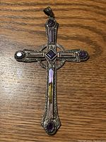 Front view of silver cross pendant with amethyst and marcasite inlays on wooden surface