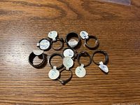 Top-down photo of 10 sterling silver rings on a wooden surface, each labeled with a size tag.