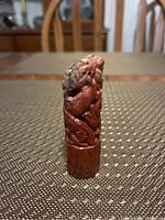 Front angled view of red and white carved stone creature showing detail on head and body