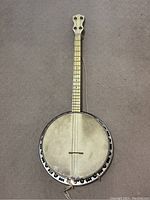 Full view of vintage banjo showing 33-inch length, circular drum head, and metal rim with decorative cutouts.