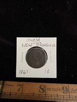Front side of the 1861 Canada New Brunswick penny showing Queen Victoria profile and handwritten labels on the white holder.