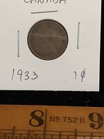 Front side of 1933 Canada penny coin showing King George V profile with inscription around the edge and part of a ruler in the image for scale.