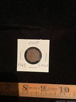 Photo of 1943 Egypt 5 mils coin front side in holder with handwritten text.