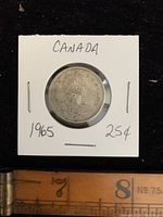 Obverse side of 1965 Canadian quarter showing Queen Elizabeth II portrait and coin holder with text.