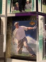 Close-up of a 'Tiger's Tales' Upper Deck golf card featuring a golfer in a white shirt swinging a club against a blue sky background.