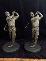 Front view showing both golfer statues, one missing the club head at the end of the club shaft.
