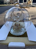 Glass orb ornament with etched snowflakes and a gold-accented angel inside, hanging loop on top