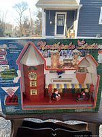 Front view of the sealed original box showing the 'Northpole Station' animated Christmas decoration with its features and size.