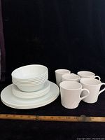 Full set of 18 dishes and 5 mugs arranged with ruler for scale, showing stacked bowls, plates, and mugs.