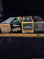 Four sleeves of golf balls lined up side by side, showing the front of the boxes featuring brand and model names.