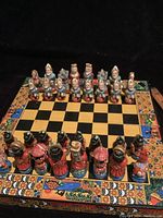 Chessboard set up with all 32 handmade and handpainted chess pieces in starting position on a colorful folding board