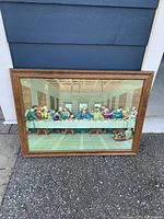 Framed vintage lithograph art of the Last Supper with clear details of the figures and background, laid on pavement showing overall condition and size.