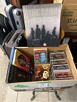 Box of various music CDs showing a wide selection of artists and albums, packed in cardboard box.