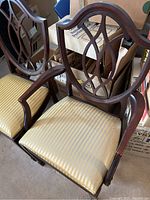 Armchair and side chair angled view showing Chippendale style back splats and plastic‐wrapped seats