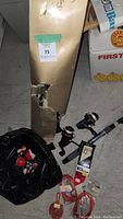 Photo of damaged gold colored box with hole exposing rod and reels, bag of bobbers and hooked items on floor next to box.