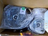 7-piece new non-stick cookware set in cardboard box wrapped in bubble wrap including pots, pans, lids, and handles.