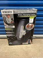 Front of box showing product name, brand, and image of the massage cushion with hand control.