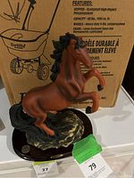 Brown standing horse statue with black mane and tail on dark wooden base, with visible price tags and background box.