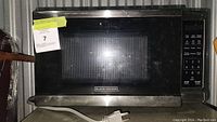 Black+Decker microwave oven front view with control panel and glass door closed.