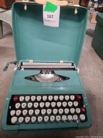 Teal vintage manual typewriter inside matching hard case, clearly showing keyboard and platen.