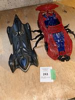 Photo of two superhero-themed toy cars on a wooden surface.