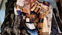 Full collection of scarves displayed together showing variety of patterns, colors, and brands including Gianni Versace branding