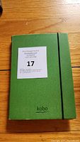 Green Kobo-branded protective case closed, showing elastic band and fabric texture.