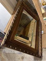 Full view of mirror leaning against basement wall showing carved frame and reflective surface
