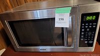 Kenmore stainless steel microwave showing front with control panel, door with handle, and auction label.
