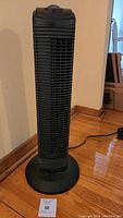 Full view of the 28-inch oscillating tower fan, showing its tower shape, black color, vertical grille, and round base.