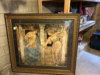 Full view of large framed artwork with two women and columns inside an ornate gold frame.