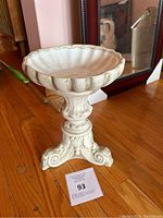 Side view of white ceramic pedestal bowl showing scalloped edge and ornate base
