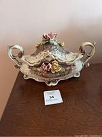 Front view of the vintage Capodimonte footed oval tureen with detailed floral decorations on the lid and handles.