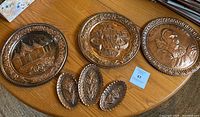All 6 copper plates shown on wooden table with scenes and floral engravings