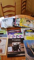 Overview of vinyl record collection displayed on a wooden table including visible titles and artist covers