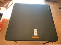 Top view of black vinyl square card table, showing vinyl surface and shape.