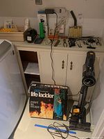 Wide view of cords, tools on counter, boxed life ladder, and LG cordless vacuum on floor