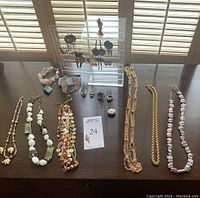 Overview of all necklaces, earrings on acrylic stand, rings, pendant and pocket watch arranged on table