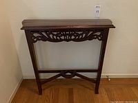Frontal view of the small Victorian hand carved wooden console table against a light wall, showing overall structure and carved apron.