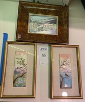 Three framed artworks displayed together, showing one larger winter scene framed in burl wood above two smaller vertical complementary bird paintings in gold frames.
